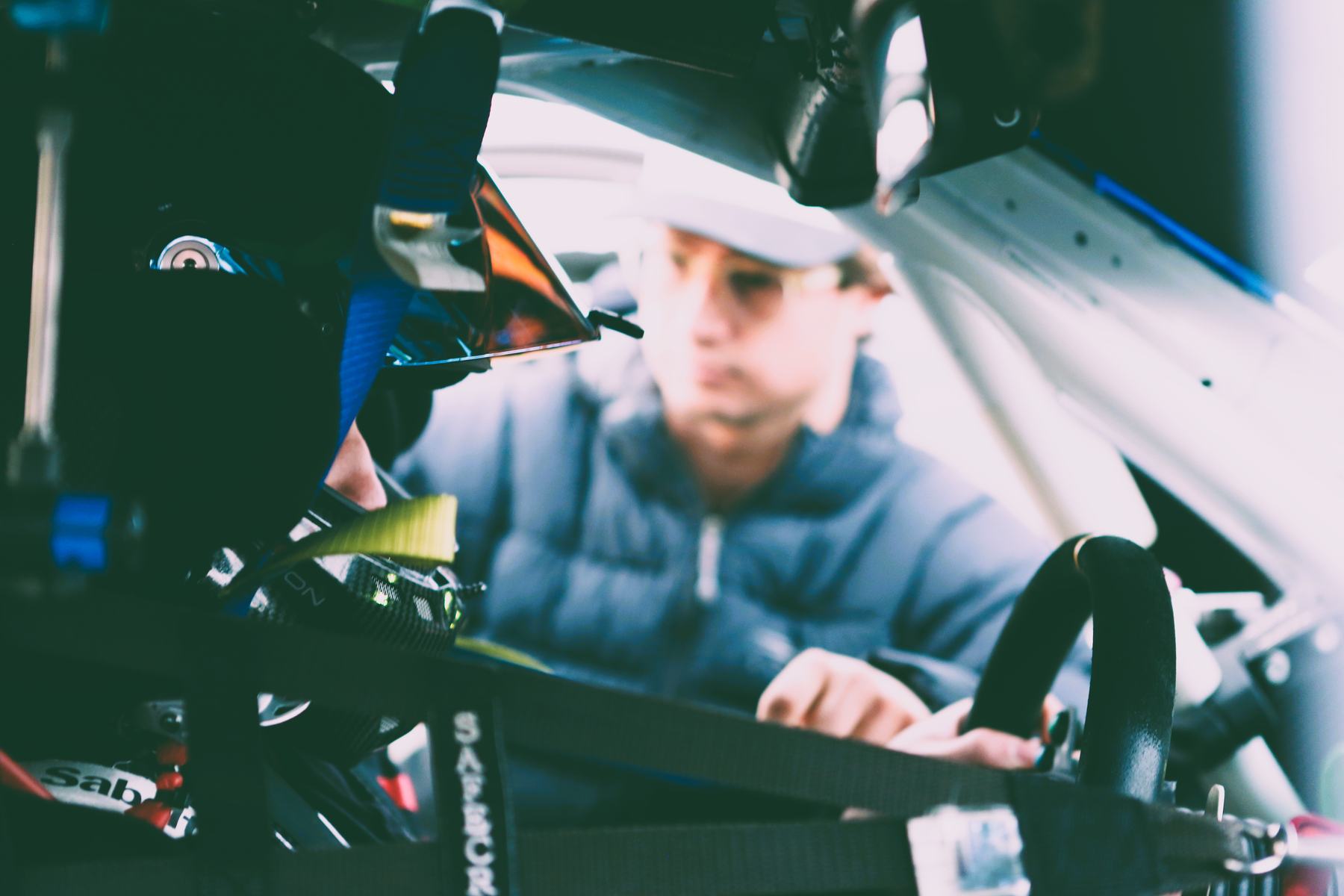 A crew member works through the roll cage, belts and hardware in the foreground.