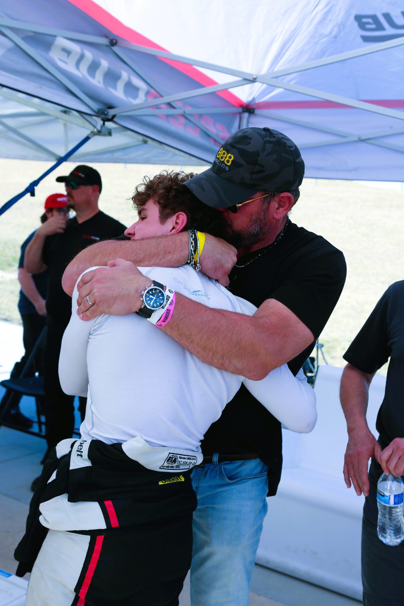 Ralph Marczynski hugs his son Brady, still in a racing suit, under the team awning.