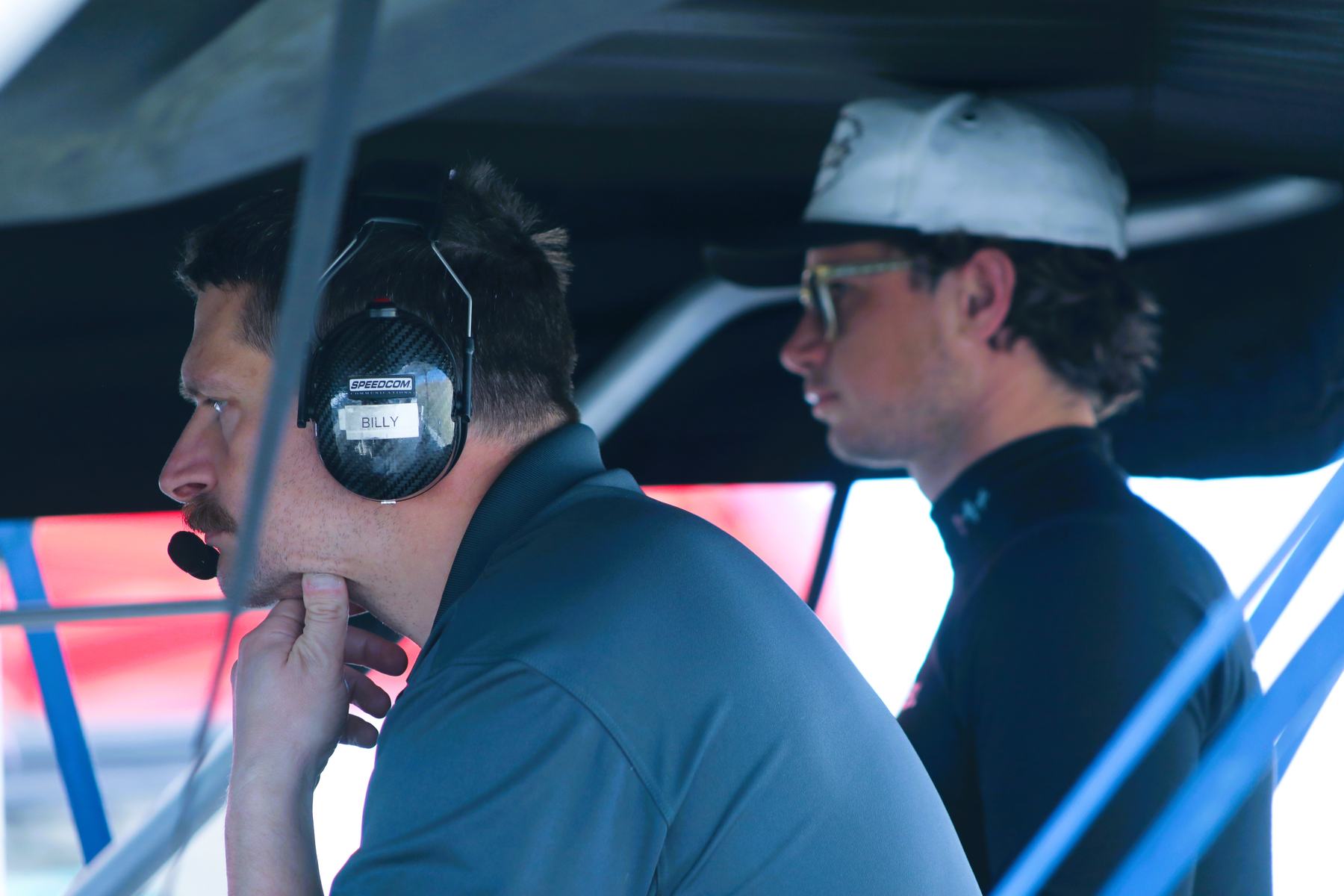 An engineer on the headset watches the session while a driver stands beside him.
